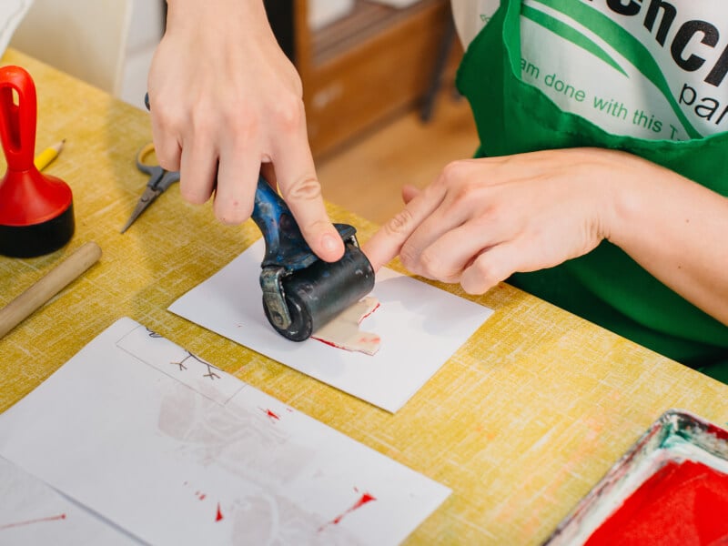 A person is rolling over their lino stamp to make lino prints.
